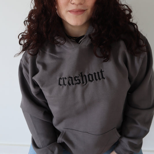 Person wearing a gray sweatshirt with 'crashout' text against a plain background
